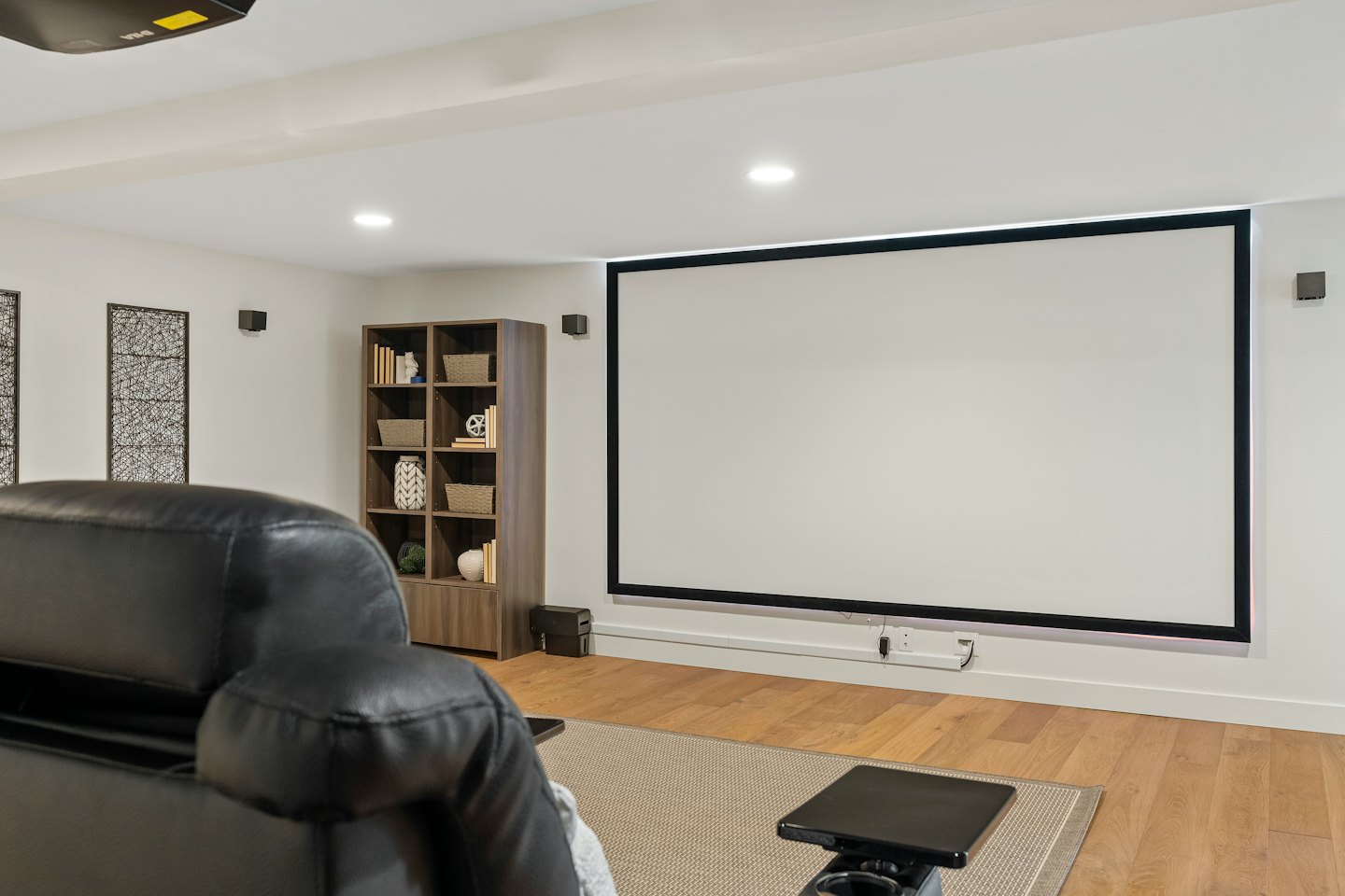 Modern home theater with a projection screen and leather recliner.